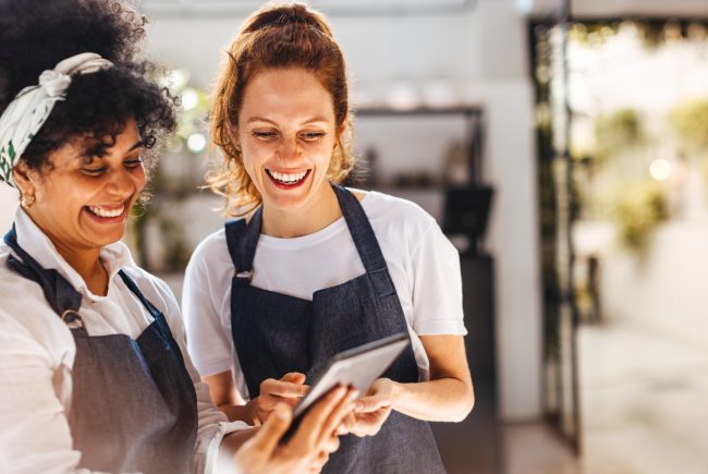 Happy,Female,Employees,Using,A,Mobile,App,On,A,Tablet
